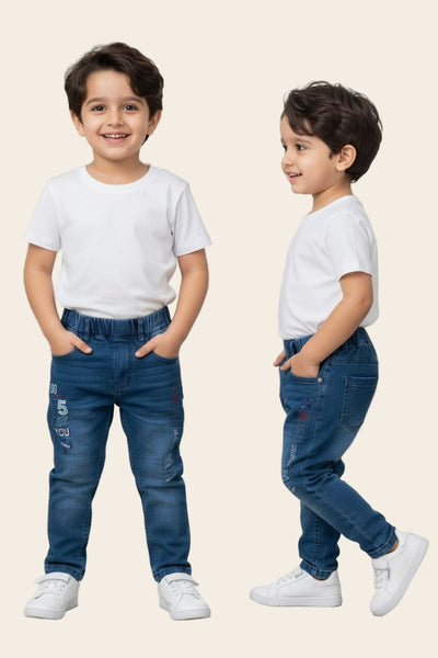 Two young boys wearing matching outfits of white t-shirts and blue jeans in a bright room.